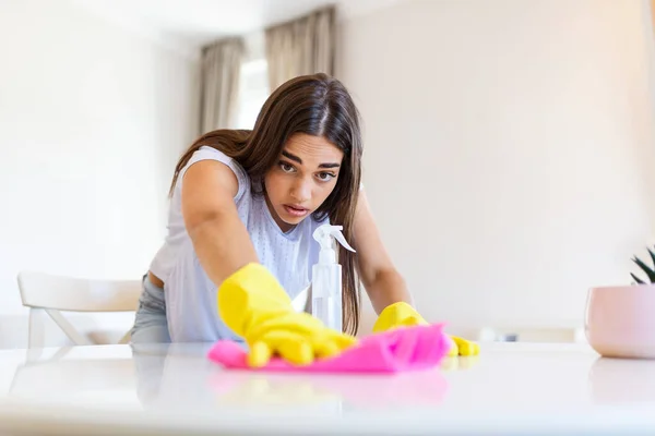 Shot of a young woman looking tired while cleaning at home. Tired young woman standing with cleaning products and equipment, Housework concept.