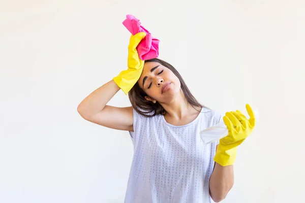 Shot of a young woman looking tired while cleaning at home. Tired young woman standing with cleaning products and equipment, Housework concept.