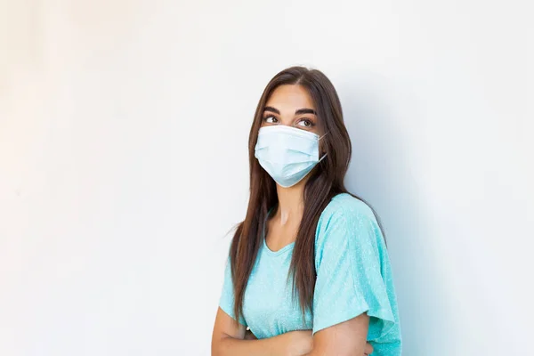 Girl in respiratory mask. Masked woman looks at camera. Cold, flu, virus, tonsillitis, respiratory disease, quarantine, epidemic concept. Beautiful caucasian young woman with disposable face mask