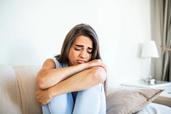 Young woman sit on couch feels unhappy desperate thinking about personal difficulties mental health problems, depressed and anxious woman need psychological support.