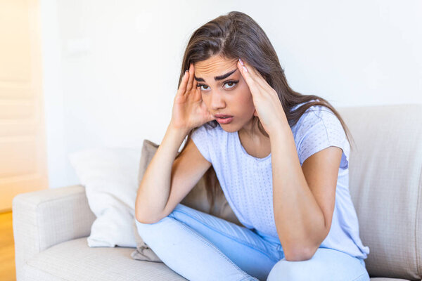 Young woman sit on couch feels unhappy desperate thinking about personal difficulties mental health problems, depressed and anxious woman need psychological support.