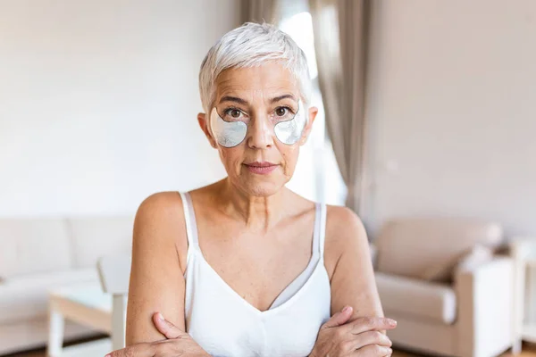 Beauty portrait of middle age woman with wrinkles and a silver patch under eyes. Collagen mask and spa concept. Copy space. Summer skin care