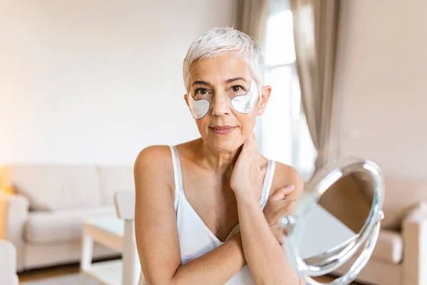 Beauty portrait of middle age woman with wrinkles and a silver patch under eyes. Collagen mask and spa concept. Copy space. Summer skin care