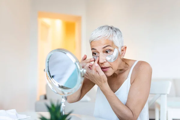 Beauty portrait of middle age woman with wrinkles and a silver patch under eyes. Collagen mask and spa concept. Copy space. Summer skin care