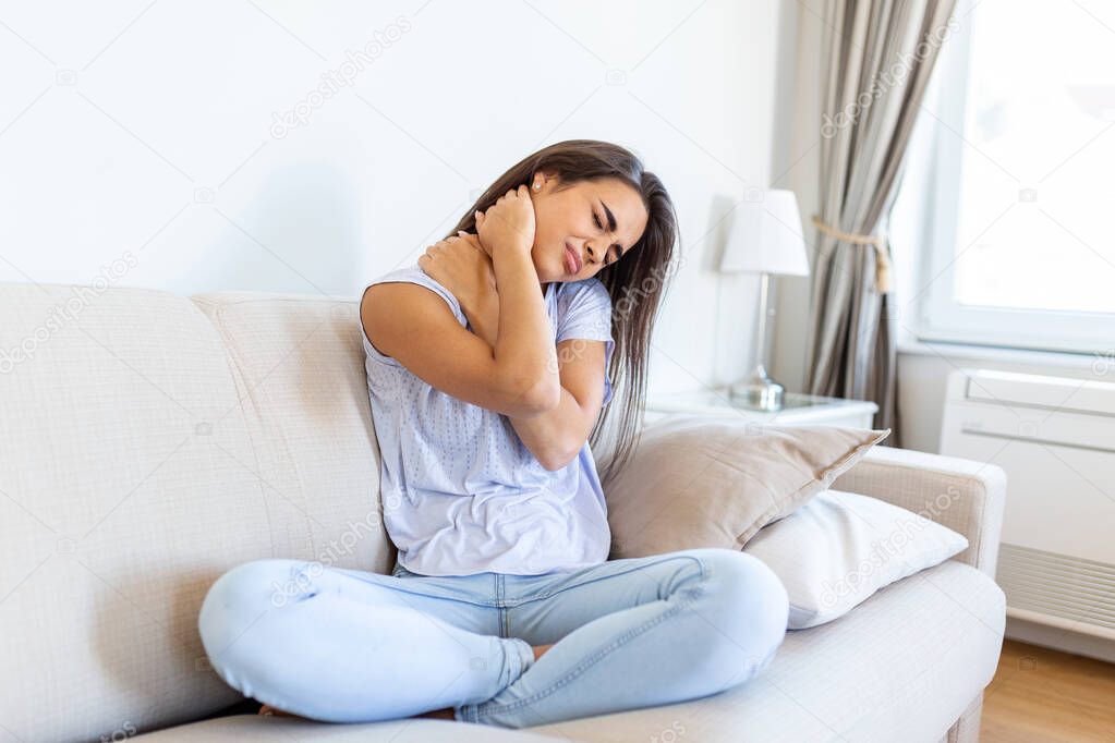 Young woman suffering from neckpain. People, healthcare and problem concept - unhappy woman suffering from neckpain at home. Neckpain caused by not taking care of health.