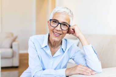 Happy old professor at home. Closeup face of mature pensive lady smiling with gray hair.
