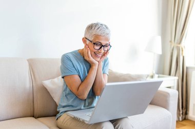 Happy smile. Elderly woman feeling happy while having video call. Senior woman sitting on the couch and having video call