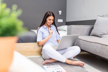 Positive young woman freelancer watching video in blog on netbook at comfortable home. Beautiful young business woman working on laptop.Freelancer connecting to internet