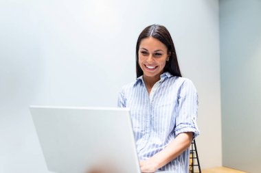 Positive young woman freelancer watching video in blog on netbook at comfortable home. Beautiful young business woman working on laptop.Freelancer connecting to internet