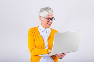 Image of cheerful mature woman standing isolated over gray background using laptop computer. Portrait of a smiling senior lady holding laptop computer
