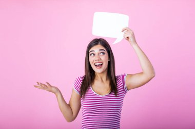 Young beautiful girl holding a bubble for text, isolated on a pink background. Young woman with smile holding blank speech bubble against background