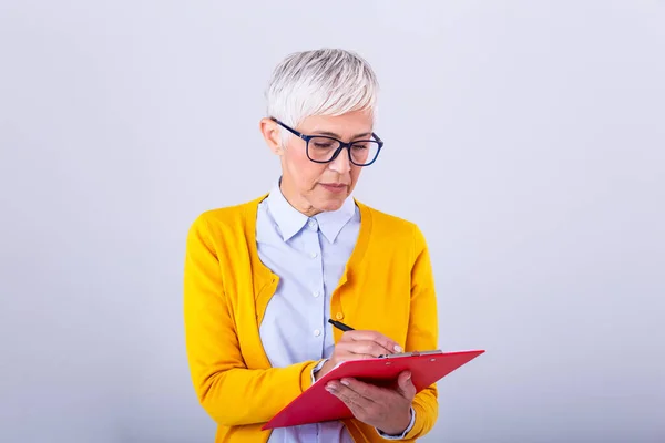 beautiful mature businesswoman writing in clipboard isolated on white. Portrait senior business women with clipboard and document in hands