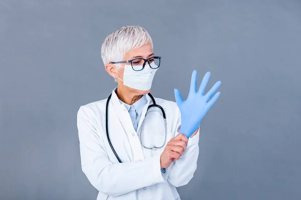 Mature Female Doctor Putting Protective Gloves Medical Protective Mask Isolated — Φωτογραφία Αρχείου