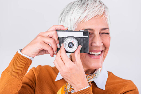 Mature female photographer taking pictures with old retro camera. Professional photographer doing a photoshoot.