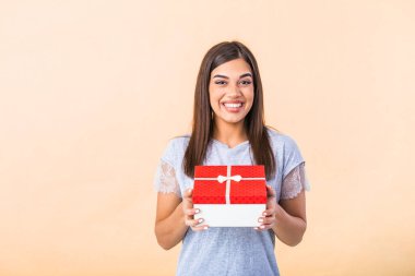 Cheerful good looking young woman holding a red Christmas gift box in her hands, against a yellow background. Concept holidays and presents