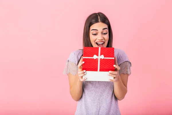 Portrait of nice girlish childish winsome attractive cheerful lady holding in hand opening large red Christmas gift box guessing isolated on bright vivid pink background