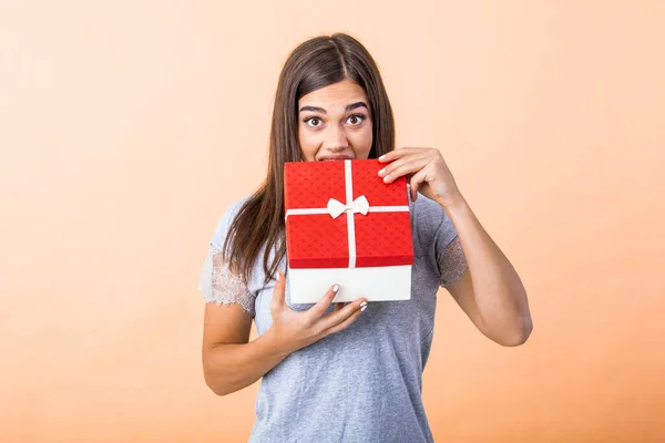 stock image Portrait of a happy smiling girl opening a Christmas gift box isolated over yellow background. Excited young casual brunette woman holding present box