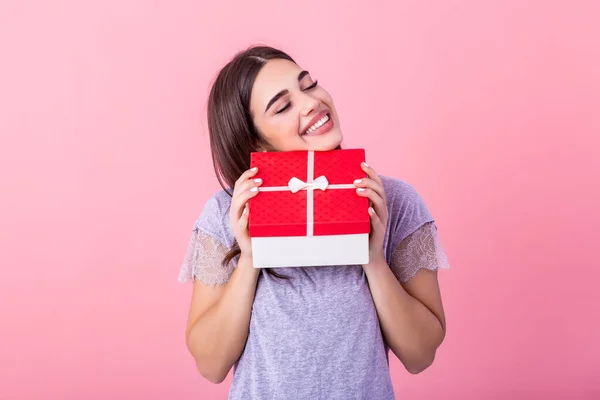 Portrait of young lovely nice sweet glamorous girl lady, wearing gray top, carrying gift box, wondering about surprise. Isolated over bright vivid pink background