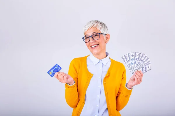 Closeup portrait super happy excited successful senior woman pensioner holding money dollar bills and credit card in hand. Positive emotion facial expression feeling. online shopping