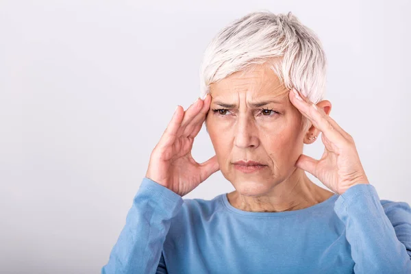 Woman suffering from stress or a headache grimacing in pain. Senior woman with migraine feeling unwell. Portrait of an attractive senior woman with a headache, feeling pain