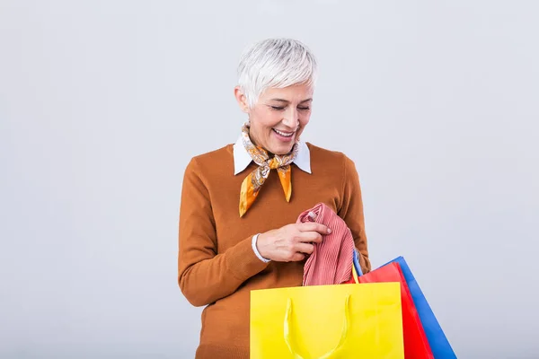 Happy mature good looking woman happy with her purchase, holding silk scarf looking at it and smiling. Shopping concept