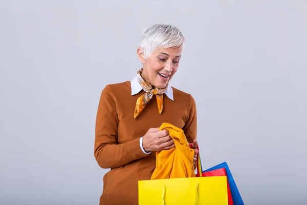Happy mature good looking woman happy with her purchase, holding silk scarf looking at it and smiling. Shopping concept