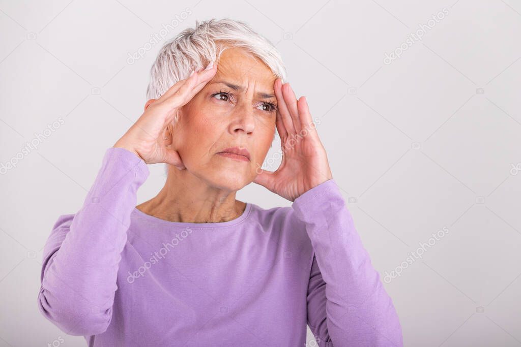 Attack of the monster migraine. Sinus pain. Unhappy Retired Senior Woman holding her head with pain expression . Face of senior woman suffering from headache