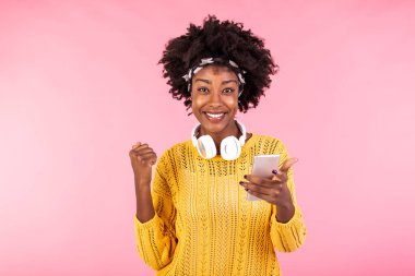 Kulaklıkla harika şarkılar dinlemenin verdiği mutluluk hissi. Elleri havada dans eden, akıllı telefon tutan, geniş gülümseyen, kulaklıkla müzik dinleyen mutlu kadın.