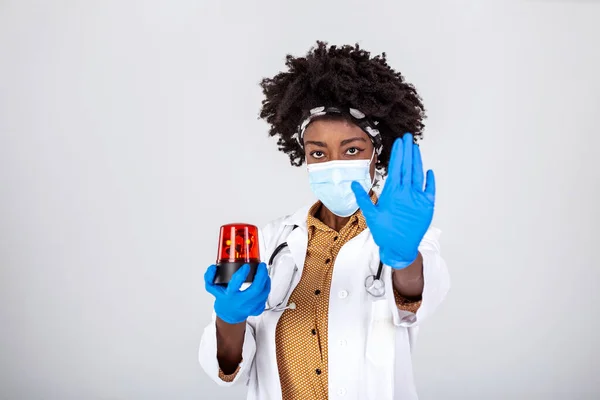Coronavirus alert. Stop covid 19. Female black doctor holding flasher siren and showing stop sign with her hand to coronavirus