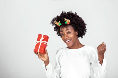 Çekici bir kızın portresi. Elinde hediye kutusu var. Açmaya hazır, beyaz arka planda izole edilmiş sıradan bir gömlek giyiyor.