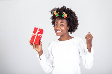 Kafasında ren geyiği boynuzları olan güzel siyah bir kadın hediye tutuyor. Hediyesi olan bir kadın. Hediyesi olan mutlu bir kız.