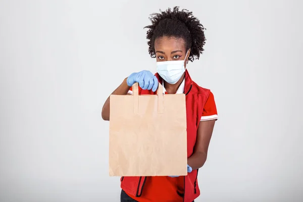 Delivery woman holding paper bag in medical rubber gloves and mask . copy space. Fast and free Delivery transport . Online shopping and Express delivery . Quarantine