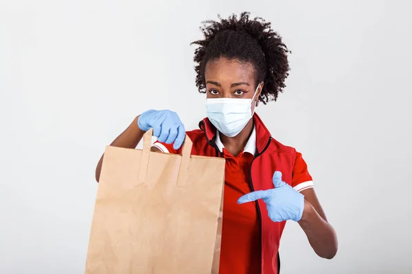 Delivery woman holding paper bag in medical rubber gloves and maskshowing thumb up. copy space. Fast and free Delivery transport . Online shopping and Express delivery . Quarantine