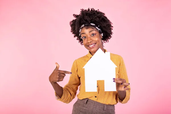 Insurance, loan, real estate and family concept. Smiling black woman buying home, holding paper house in hands and smiling, paying debt, standing white background happy