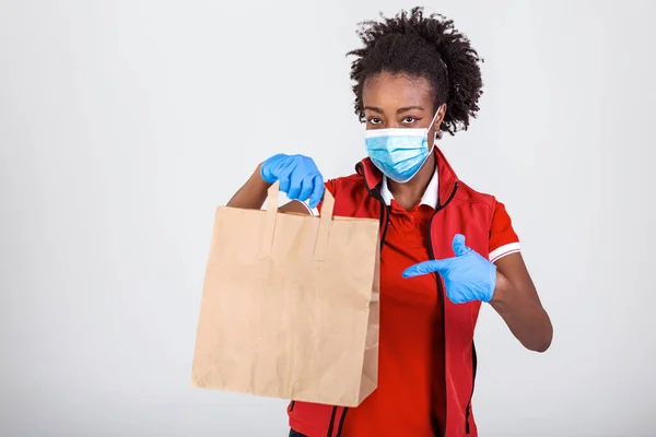 Delivery woman holding paper bag in medical rubber gloves and maskshowing thumb up. copy space. Fast and free Delivery transport . Online shopping and Express delivery . Quarantine