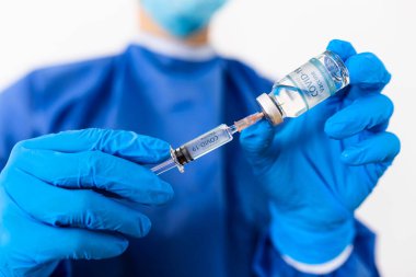 Coronavirus COVID-19 aşısı. Corona virüsü aşısını ve şırıngayı elinde tutan doktor COVID-19 enfeksiyonunu önlemek için kullanıyor. Tıp ve Sağlık Hizmetleri kavramı.