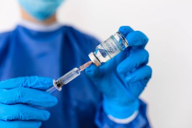 Covid-19 Corona virüsüne karşı yapılan kavramsal mücadele, laboratuvarda bulunan doktor ya da bilim adamı çocuk ya da daha yaşlı yetişkinler için sıvı aşı içeren bir şırınga taşıyor, kavram: hastalıklar, tıbbi bakım, bilim.