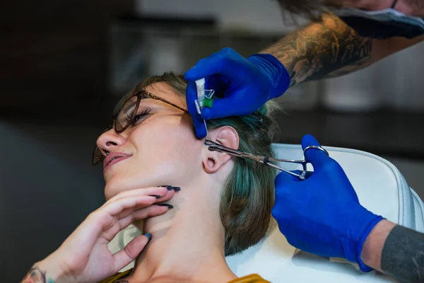 鼻を突かれた女性の肖像画 滅菌針とラテックス手袋で鼻を貫通するプロセスを示す男 鼻孔ピアス手順 — ストック写真