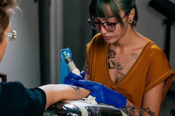 手にタトゥーを作成のプロセスを示す女性タトゥー マスターの肖像画 — ストック写真