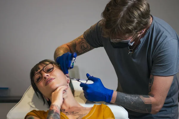 Young Woman Getting Her Ear Pierced Man Showing Process Piercing — Stock Photo, Image