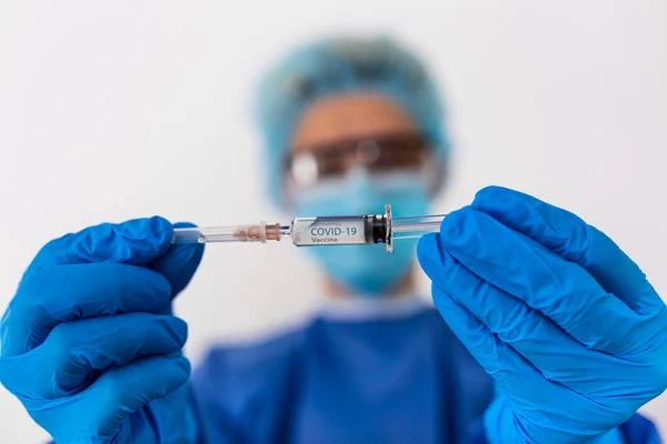 中国のコロナウイルスの流行 防護服を着た医師の女性とマスクは注射器とワクチンを保持しています インフルエンザコロナウイルスからのワクチン — ストック写真