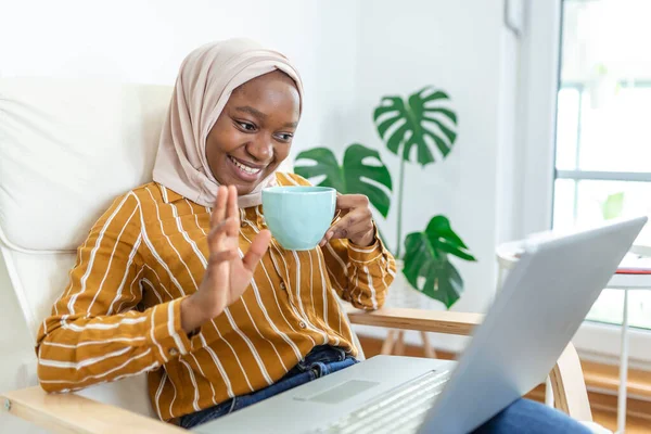 Muslim woman working with computer. Arab Young business woman sitting at her desk at home, working on a laptop computer and drinking coffee or tea. Muslim woman working at a home and using computer.