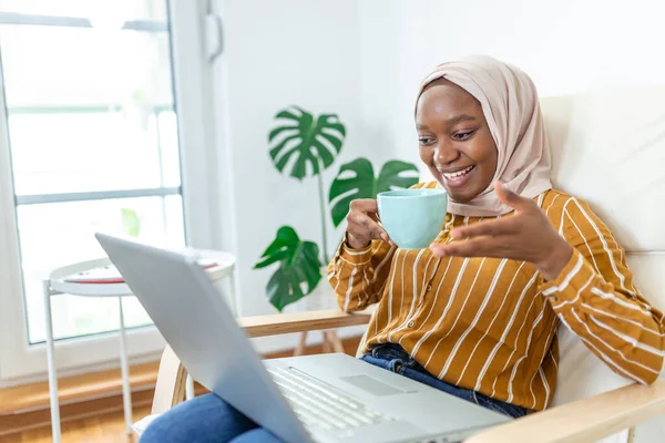 Muslim woman working with computer. Arab Young business woman sitting at her desk at home, working on a laptop computer and drinking coffee or tea. Muslim woman working at a home and using computer.