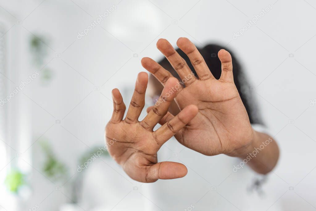 Woman defending herself from attack. Stop. Hands outstretched. campaign stop violence against women. African American woman raised her hand for dissuade with copy space