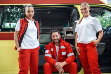 Mutlu, gülümseyen doktorlar ambulansın yanında duruyor..