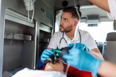 Acil yardım ekibi, yaralı hastaya sağlık hizmetleri hastanesine giderken tıbbi yardım sağlayın. Acil Bakım Asistanı Ambulans 'ta, Aralıksız Havalandırma Maskesi Kullanıyor. Yakın çekim..