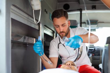 Doktor, nefes almayan hasta için endotrakeal entübasyona hazır. Kadın sağlık görevlisi serum solüsyonu tutuyor. Sağlık görevlileri, hastaneye giderken yaralanan bir hastaya tıbbi yardım sağladı.