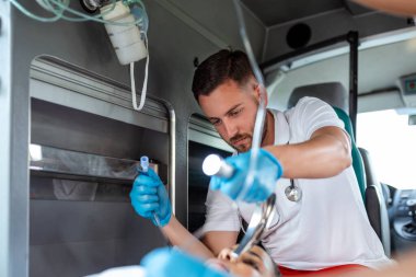 Doktor, nefes almayan hasta için endotrakeal entübasyona hazır. Kadın sağlık görevlisi serum solüsyonu tutuyor. Sağlık görevlileri, hastaneye giderken yaralanan bir hastaya tıbbi yardım sağladı.