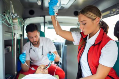 Doktor, nefes almayan hasta için endotrakeal entübasyona hazır. Kadın sağlık görevlisi serum solüsyonu tutuyor. Sağlık görevlileri, hastaneye giderken yaralanan bir hastaya tıbbi yardım sağladı.