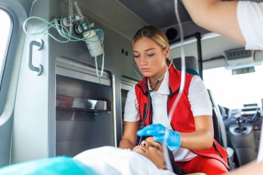Doktorların acil durumu ya da sağlık görevlileri yaşlı bir kadın hasta ambulansta sedyede yatarken onunla birlikte çalışıyorlar..